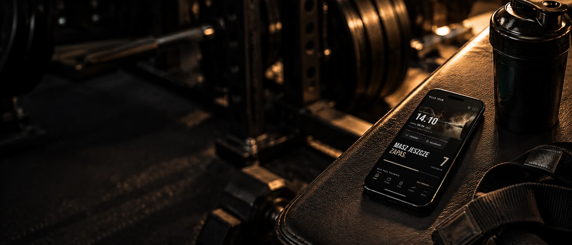 Aplikacja KillaTeam na telefonie leżącym na ławce treningowej — ekran Start z najbliższym treningiem